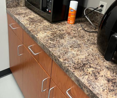 A break room counter, cabinets and microwave wiped down.