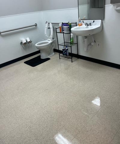 A commercial restroom with a clean sink and toilet and a freshly mopped floor.