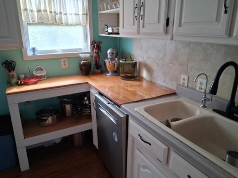 Kitchen counters, sink and cabinets wiped down in a lived-in home.