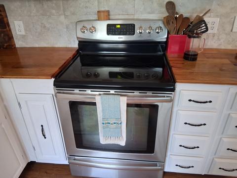 A clean stainless steel stove and range in a lived-in kitchen.