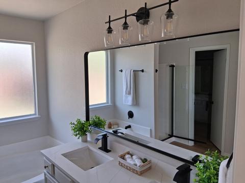 A bathroom vanity and mirror with black fixtures, wiped clean for a move-in.