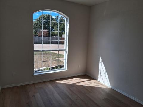 An empty bedroom with an arched window and clean wood-look floors, ready for move-in day.