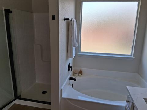A garden tub and glass shower, wiped down and gleaming after a move-in cleaning.