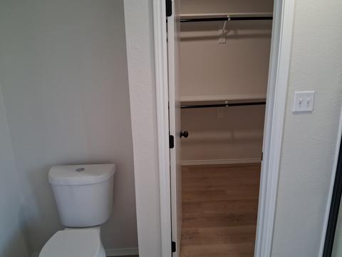 A clean toilet beside the doorway into an empty, freshly cleaned closet.