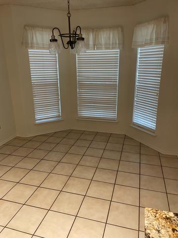 An empty breakfast nook with bay windows and freshly cleaned floors.