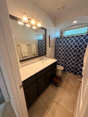 A hall bathroom with a clean vanity, mirror and tub after a move-out cleaning.