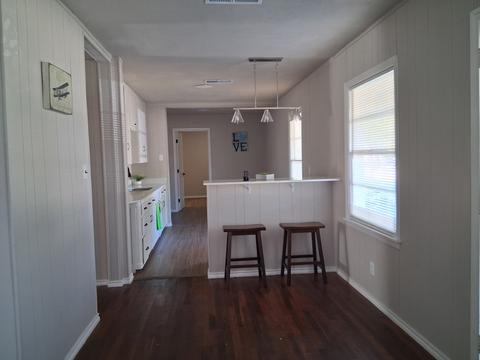 A long hallway leading to a clean, empty kitchen after a move-out cleaning.