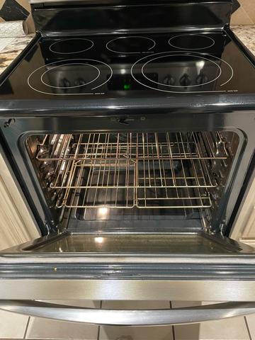 An open oven with a clean interior and racks after a move-out cleaning.