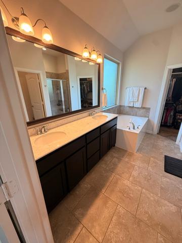 A primary bathroom vanity with clean counters and a shining mirror.