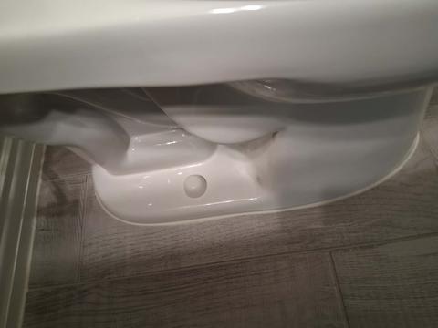 A close-up of a clean toilet base and the floor around it.