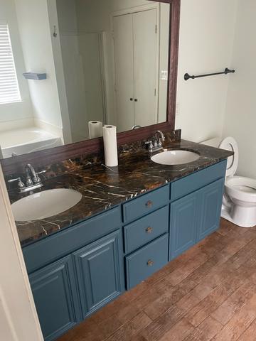 A bathroom vanity with a dark counter and clean sinks after a move-out cleaning.