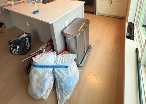 Bagged trash and cleaning supplies by the kitchen island during a cleaning.