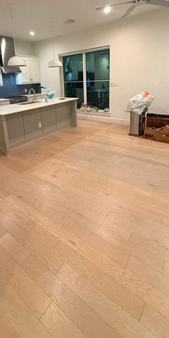 An open kitchen and living area mid-clean, with trash bagged and supplies staged.