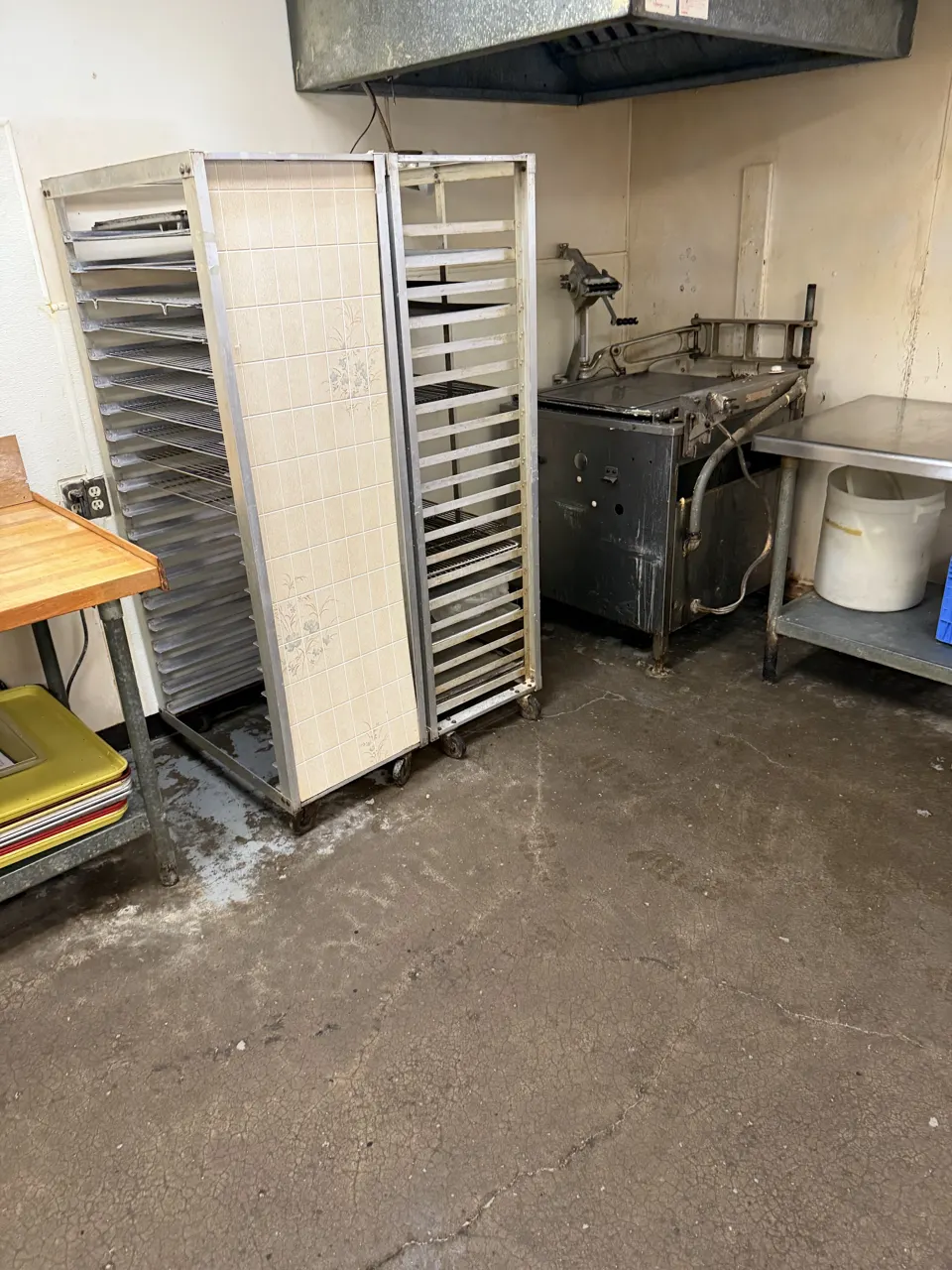 DURING: commercial kitchen with racks and equipment during a heavy-duty cleanup