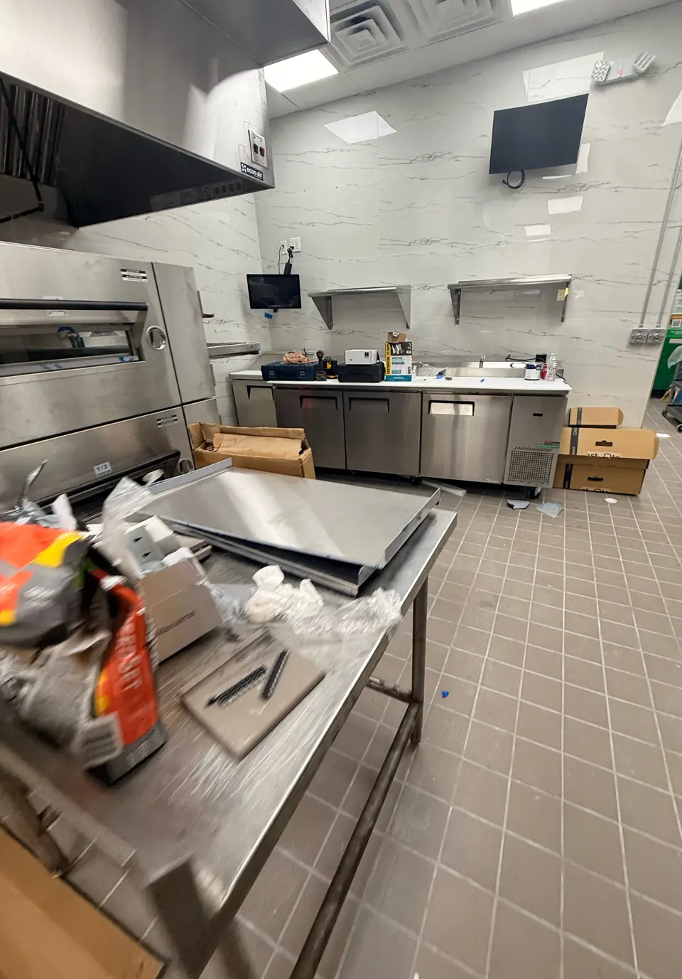 BEFORE: new commercial kitchen with boxes, plastic wrap and debris before post-construction cleaning