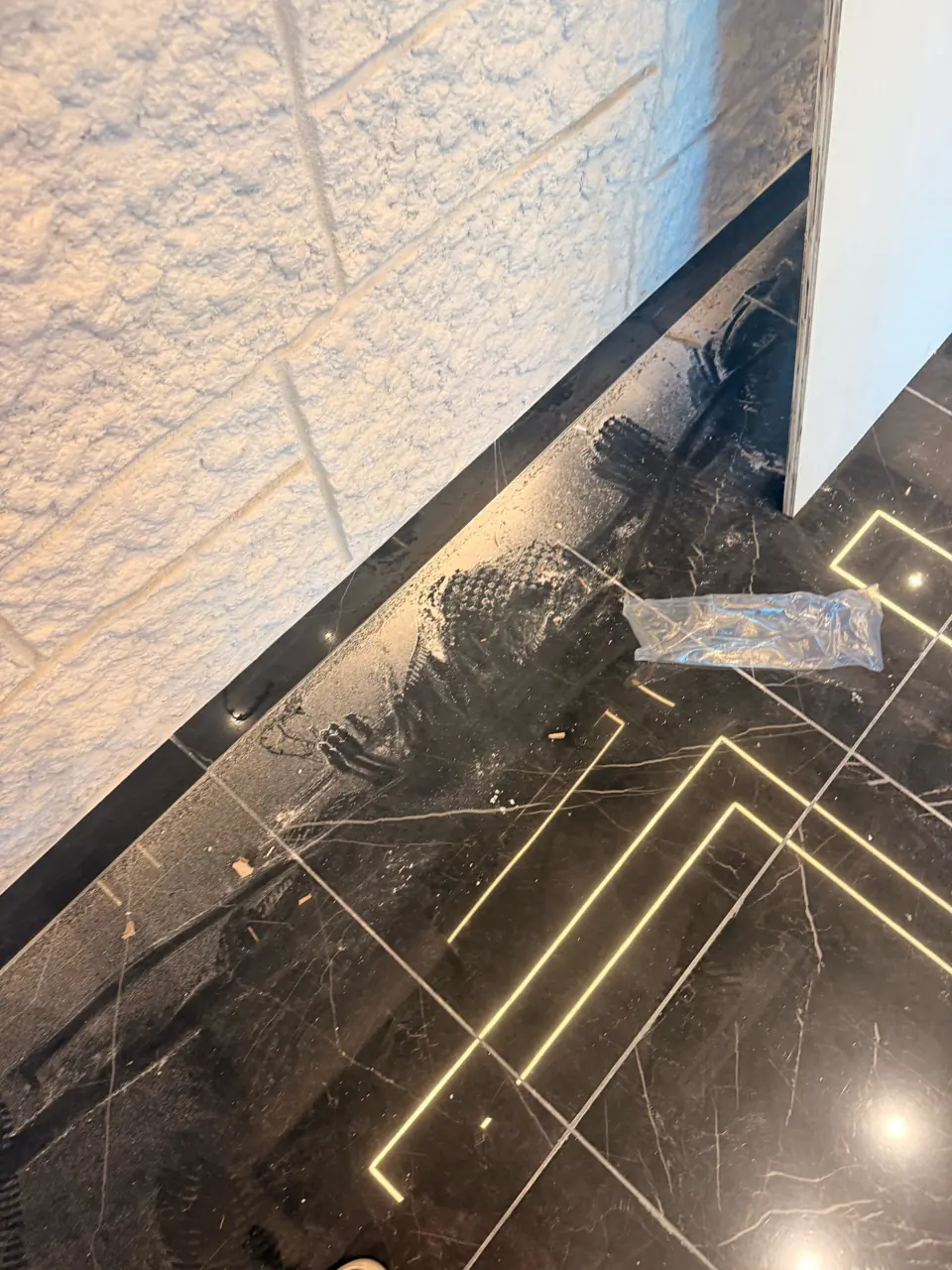 BEFORE: dusty black marble floor with footprints and debris, before post-construction cleaning